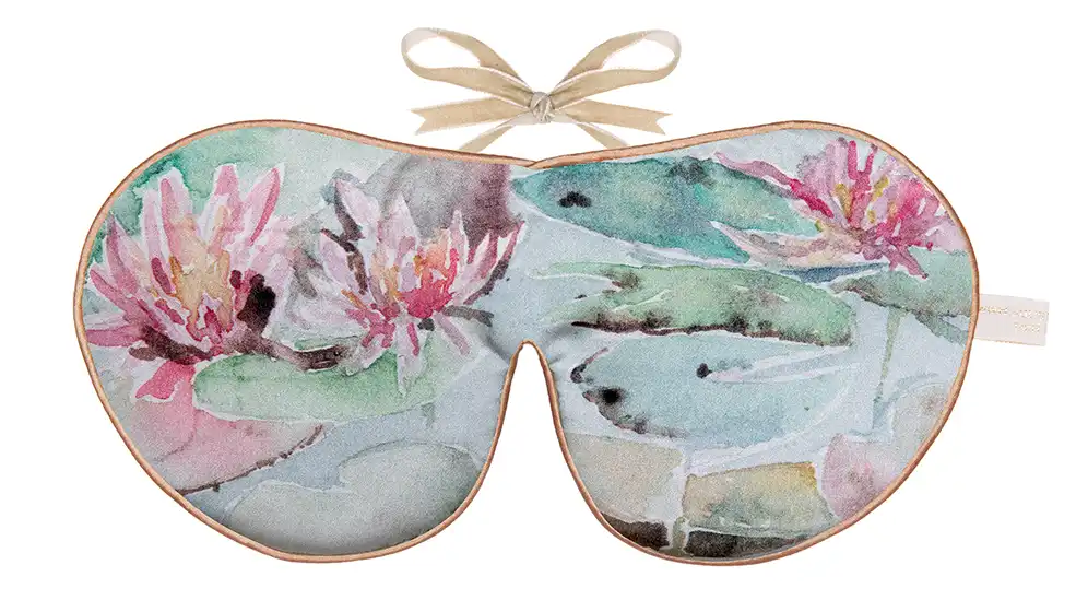 Silk sleep mask with a painted water lily scene, featuring pink blossoms and green lily pads on soft blue water.