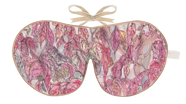 Silk sleep mask with a detailed pattern of pink, mauve, and red leaves layered over a subtle textured background.