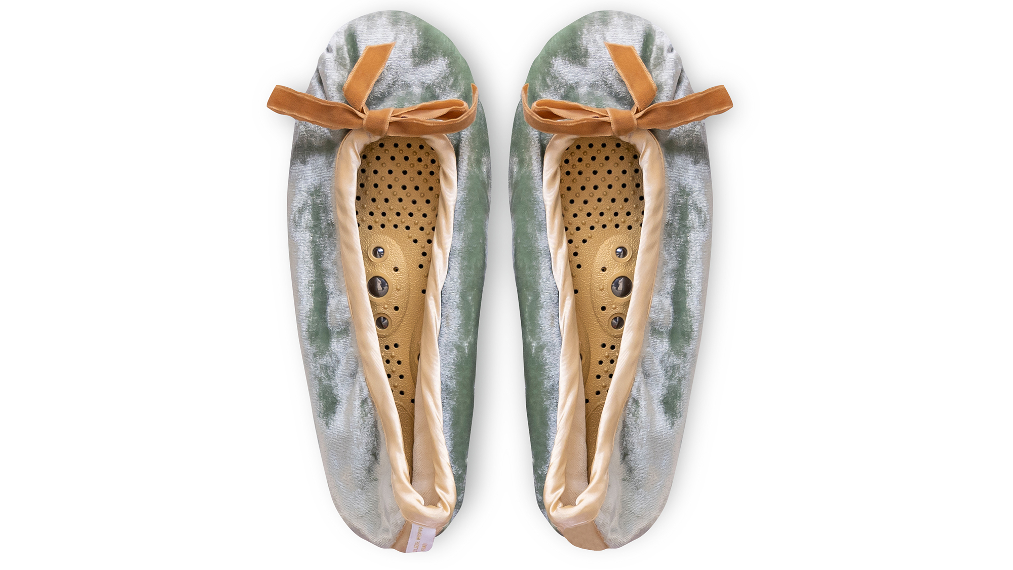 A flat image of a pair of Holistic Silk ballerina style Massaging Slippers in a Jade Silk Velvet colour with a honey colour velvet bow tie at the top edge of the toe area. The slippers are side by side with the toes at the top of the image. The magentic insoles inside the slippers are visable.