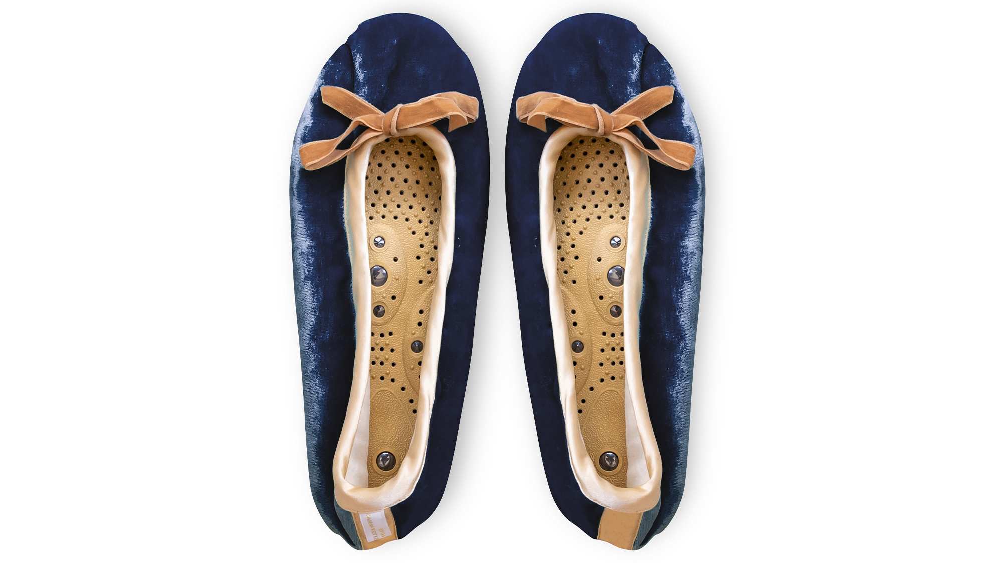 A flat image of a pair of Holistic Silk ballerina style Massaging Slippers in a Navy Silk Velvet colour with a honey colour velvet bow tie at the top edge of the toe area. The slippers are side by side with the toes at the top of the image. The magentic insoles inside the slippers are visable.