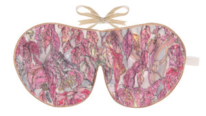 Flat image of the Holistic Silk Excluisve Silk Sleep Mask with a watercolour effect hand drawn design featuring trailing leaves in a red, purple and pink colours with Honey colour piping and a Honey colour velvet bow above it on a clear white background.