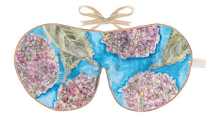 Flat image of the Holistic Silk Excluisve Silk Sleep Mask with a watercolour effect hand drawn Hydrangea Flower design with Honey colour piping and a Honey colour velvet bow above it on a clear white background.