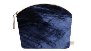 A flat image of the Holistic Silk Lavender Make Up Bag in Navy Silk Velvet.The make up bag is stood up and is wider at the top than the bottom, it has a curved zipped top which has a honey colour piping outlining it and the zip pull hanging to the top left of the bag.