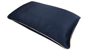 A flat image of the Holistic Silk Pillowcase in Navy colour Mulberry Silk laid diagonally across the shot showing the honey coloured piping.