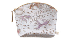 A flat image of the Holistic Silk Lavender Make Up Bag in a Silver Fish Brocade on a white background. The design shows pink colour abstract koi carp on a silver background. The wash bag is stood up and is wider at the top than the bottom, it has a curved zipped top which has a honey colour piping outlining it and the zip pull hanging to the top left of the bag.