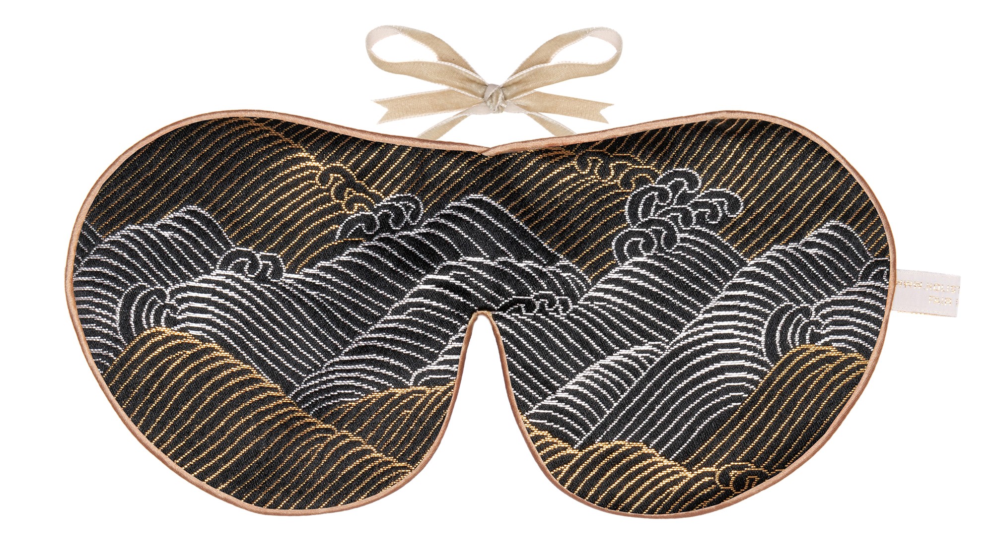 Flat image of the Holistic Silk Limited Edition Brocade Sleep Mask in a Black and gold waves deisn colour with Honey colour piping and a Honey colour velvet bow above it on a clear white background.