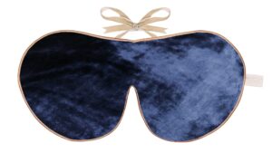 Flat image of the Holistic Silk, Silk Velvet Sleep Mask in a Navy colour velvet with Honey colour piping and a Honey colour velvet bow above it on a clear white background.