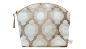 A flat image of the Holistic Silk Wash Bag in a British Jade Brocade on a white background. The design shows an abstract 2 toned pale jade rounded flower in a linear design on a broze gold background. The wash bag is stood up and is wider at the top than the bottom, it has a curved zipped top which has a honey colour piping outlining it and the zip pull hanging to the top left of the bag.