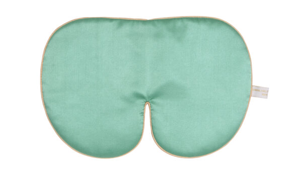 An oversized jade‑green silk sleep mask with smooth fabric, gold edging, and a soft curved shape.