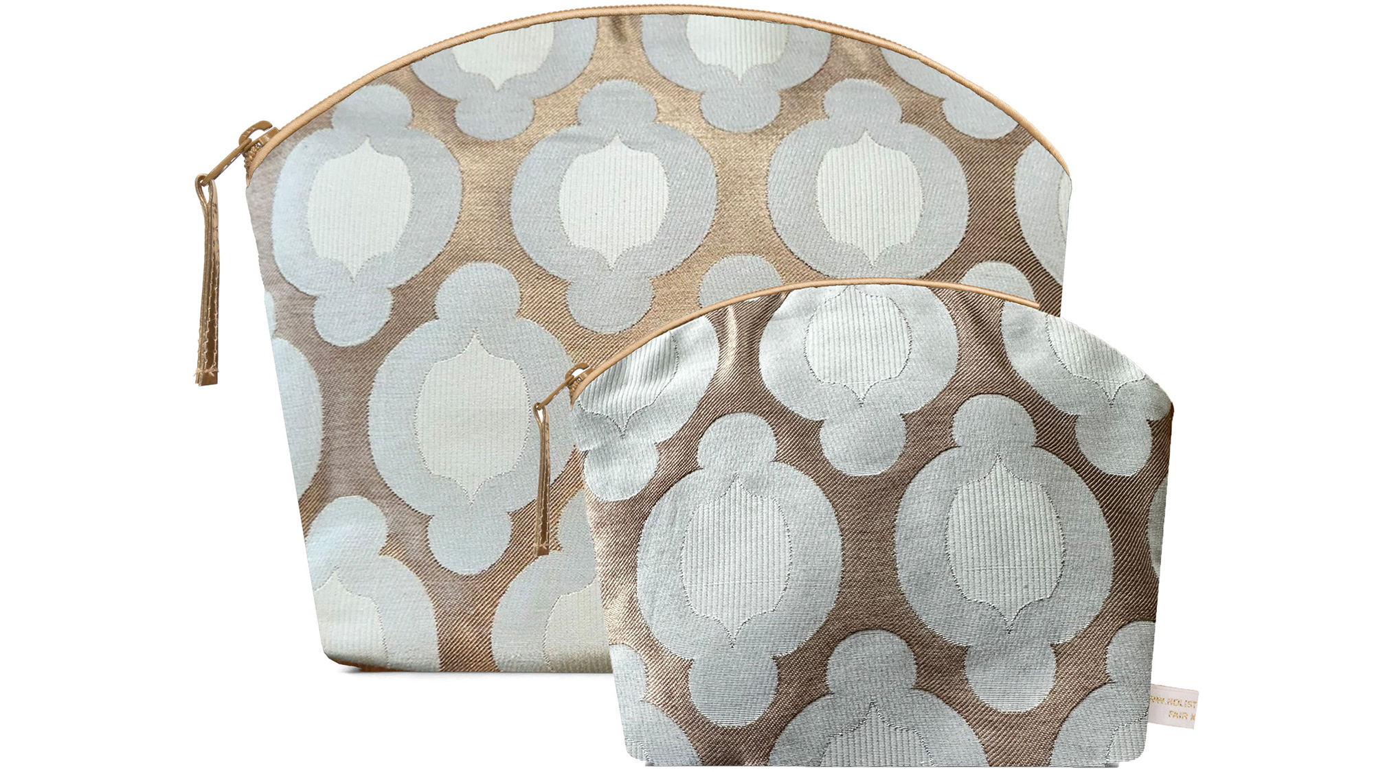 A flat image on a white background showing the Holistic Silk Lavender Wash Bag at the rear with the Holistic silk Lavender Make up bag in front to demonstrate the size difference. Both bags are in a British Jade Brocade design which has an abstract 2 toned pale jade rounded flower in a linear design on a bronze gold background. Both bags are stood up and each are wider at the top than the bottom, have curved zipped tops which have honey colour piping outlining them and the zip pulls are hanging to the top left of each bag.