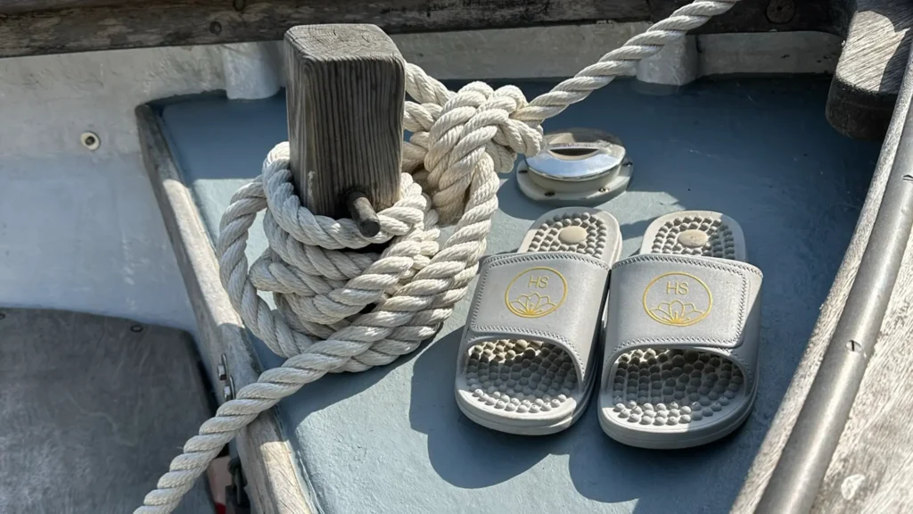Silver grey sliders on the deck of a small row boat with a coiled rope behind