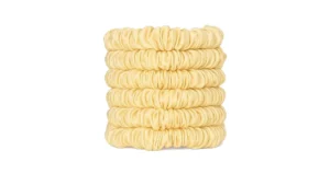 A stack of skinny silk scrunchies in a Cream shade, neatly arranged to show their smooth gathered texture