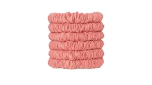 A stack of skinny silk scrunchies in a Rose Pink shade, neatly arranged to show their smooth gathered texture