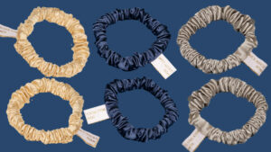 Six satin silk crunchies in cream, navy, and silver arranged on a dark blue background, each with a small white tag.