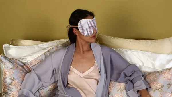 Person resting on cushions wearing Foxgloves exclusive silk sleep mask with honey trim