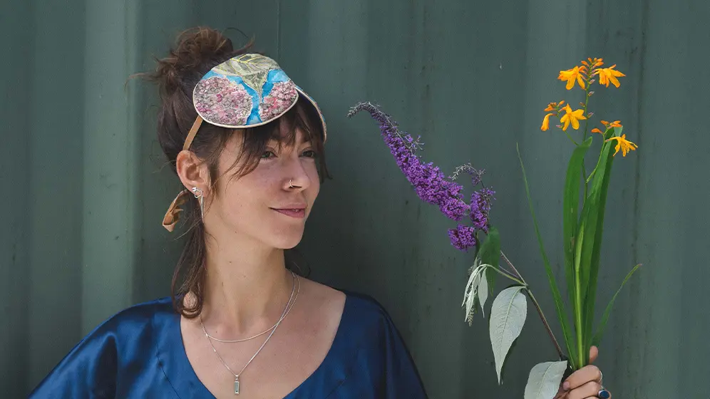 Person holding flowers while wearing Hydrangea exclusive silk sleep mask with honey piping