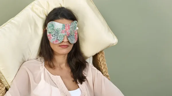 Person resting on chair wearing Nasturtium exclusive silk sleep mask with honey‑coloured trim