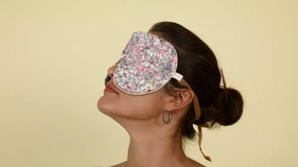 Side profile of person wearing Succulent exclusive silk sleep mask with honey trim on a warm neutral background
