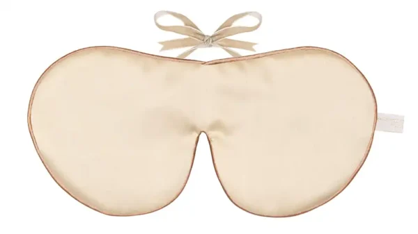 Cream silk sleep mask with a soft bow tie fastening.