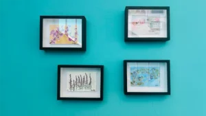Four framed botanical art prints by Joanna Weakley, arranged on a jade wall, featuring delicate floral illustrations in black frames with white mounts.