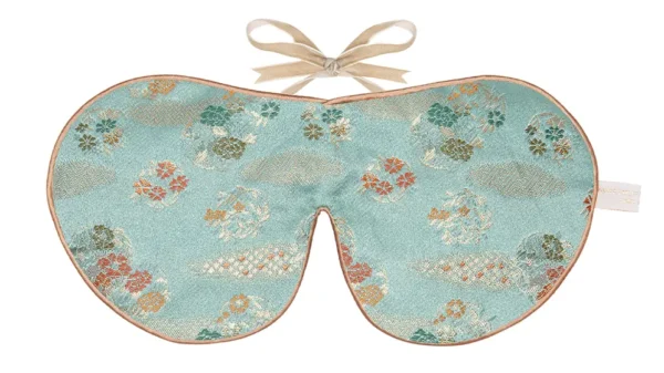 Jade green silk sleep mask with delicate Japanese floral pattern and honey coloured piping with ribbon tie fastening