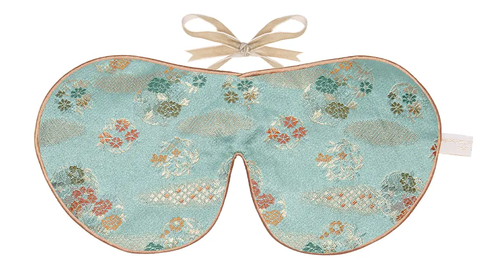 Jade green silk sleep mask with delicate Japanese floral pattern and honey coloured piping with ribbon tie fastening