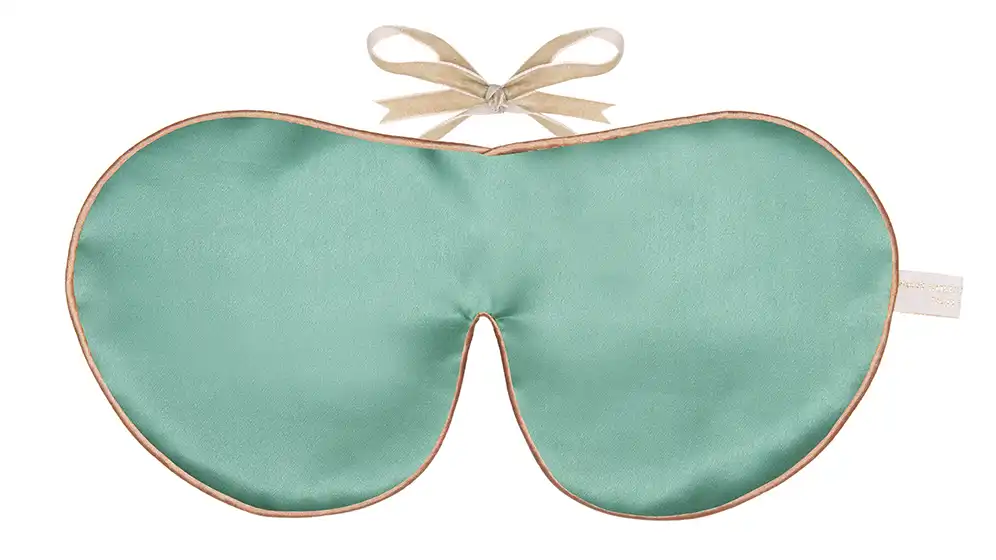 Jade silk sleep mask with honey‑coloured piping and silk ribbon tie, shown flat on a white background.