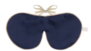 Navy silk sleep mask with honey‑coloured piping and silk ribbon tie, shown flat on a white background.
