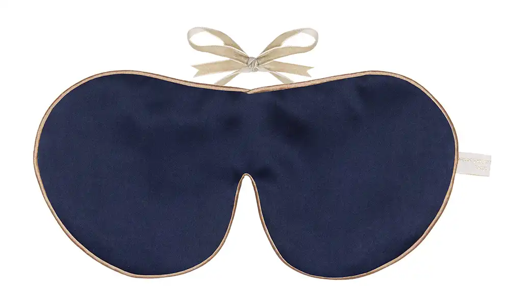 Navy silk sleep mask with honey‑coloured piping and silk ribbon tie, shown flat on a white background.