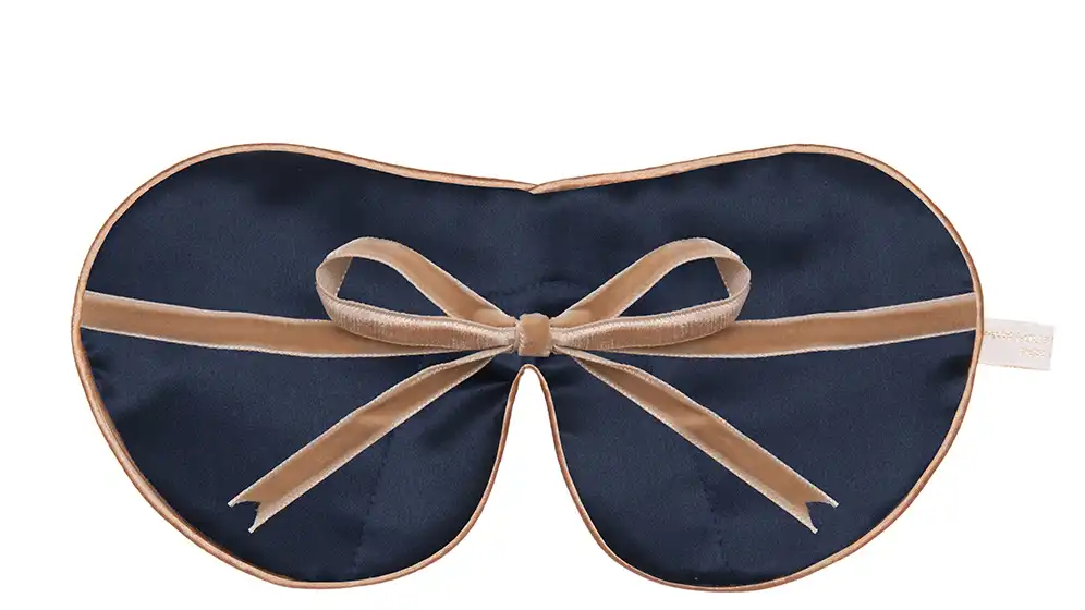 Flat image of the reverse of the Holistic Silk Classic, Unscented & Exclusive Silk Sleep Masks showing the Navy reverse, Honey colour piping and the Honey colour velvet bow tied and sitting across the middle of the mask.